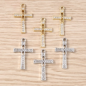 Macro detail of gold and silver cross pendants with infinity symbol and white rhinestones
