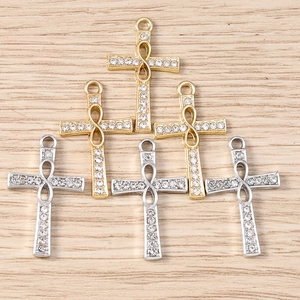 Macro shot of cross and infinity pendants with micro-pave crystals on wooden background