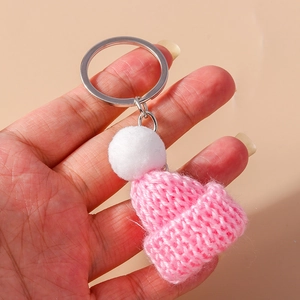 Detailed close-up of a pink knitted mini hat keychain with a white pompom held in hand