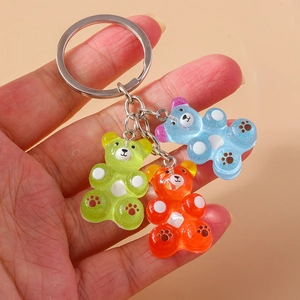 Three translucent gummy bear keychains in green, orange, and blue with glitter details