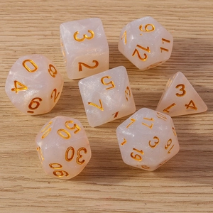 Set of 7 pearlescent pink translucent polyhedral dice with gold numbers on wood