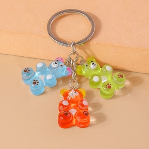 Detailed view of three gummy bear keychains in blue, green, and orange glitter resin