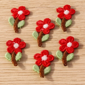 Detail of 6 floral embroidered Christmas patches with red petals and green leaves