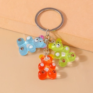 Close-up of three cute jelly bear keychains in blue, orange, and green resin materials