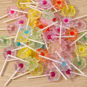 Detailed macro view of colorful resin daisy lollipop charms with metal hooks on wood