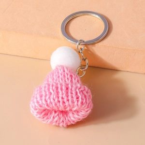 Detailed macro view of pink knitted mini hat keychain with a soft white pompom