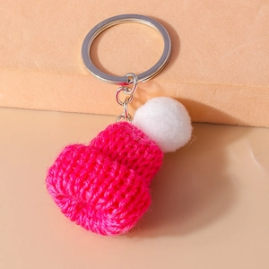 Detailed macro view of a rose red mini knitted hat keychain with a white pom-pom detail