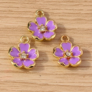 Detailed macro view of purple enamel flower pendants with gold plating and sparkling zircon