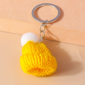 Detailed view of yellow mini knitted hat keychain with white pompom and silver ring
