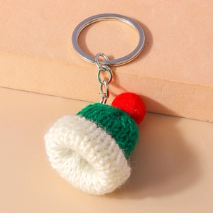 Macro detail of handmade Christmas knit hat keychain with festive red pompom and silver ring