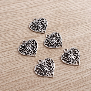 Fünf antike versilberte Herz-Schmetterling-Anhänger für DIY-Schmuck auf Holzgrund