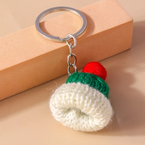 Detail of a mini knitted hat keychain with green and white yarn and red pompom