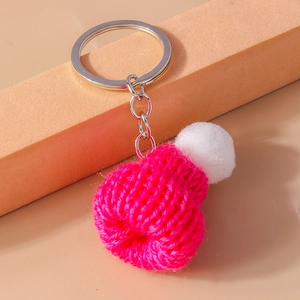 Detailed close-up of rose pink knitted mini hat keychain with soft white pompom