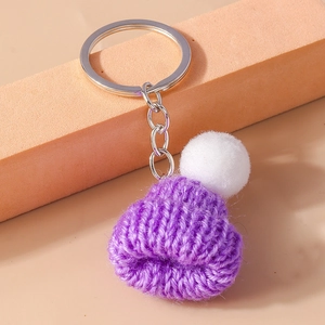 Detail of purple knitted beanie keychain with white pompom on silver ring
