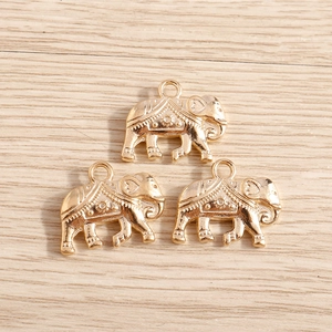 Drie vergulde olifantenhangers voor DIY sieraden maken op houten achtergrond