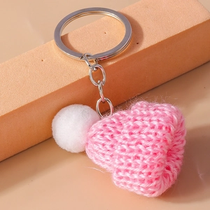 Macro detail of a pink knitted mini hat keychain with white pompom and metal ring