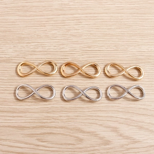 Polished gold and silver infinity symbol alloy pendants on a light wood background