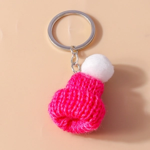 Close-up of pink knitted beanie keychain with white pompom and silver metal ring