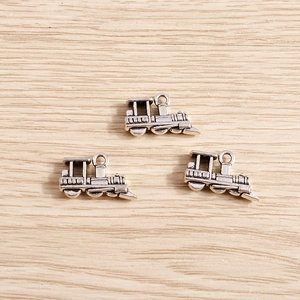 Detail of vintage silver steam locomotive pendants on light wood background for DIY jewelry