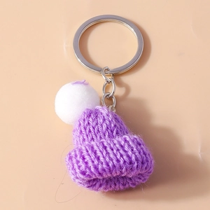 Detailed close-up of a purple knitted mini hat keychain with a white pom-pom detail