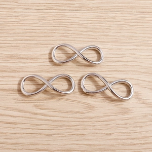 Macro shot of three silver infinity charm connectors for DIY jewelry making on wood background
