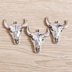 Macro detail of three vintage bull head skull charms with antique silver finish