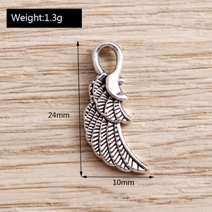 Macro shot of a vintage silver alloy wing pendant showing detailed 24x10mm dimensions
