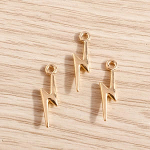 Golden alloy lightning bolt charms for DIY jewelry making on a light wood background
