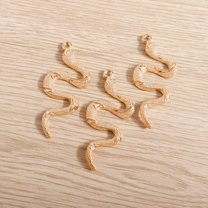 Three snake-shaped metal pendants with textured scales for DIY jewelry making