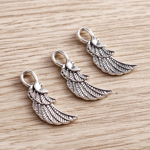 Macro detail of retro silver alloy angel wing pendants with vintage metallic textures