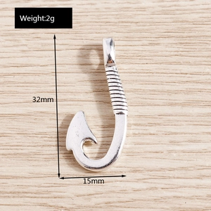 Macro detail of silver fish hook pendant showing 32mm height and textured metal design