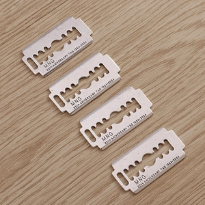 Silver blade pendants with anniversary engraving on light wood background, set of four
