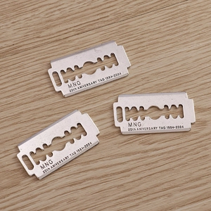 Three pieces of silver razor blade alloy pendants with engraved anniversary text on wood