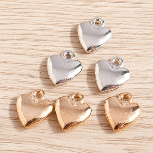Minimalist 3D heart pendants in gold and silver finish on a light wood background