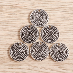 Close-up of vintage silver alloy round pendants with spiral woven texture for DIY jewelry
