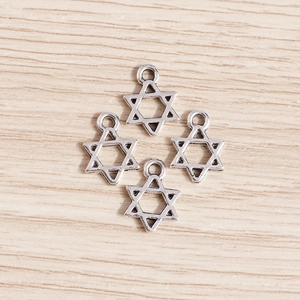 Detailed top view of four silver-plated hollow star pendants on light wood background