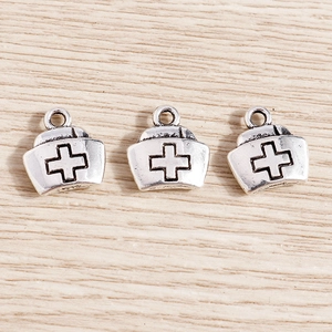 Macro detail of vintage silver nurse hat pendants with cross engraving for DIY jewelry