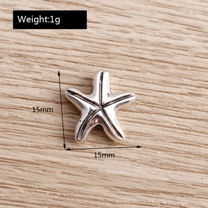 Macro shot of 15mm silver alloy starfish charms on a light wood background with 1g weight detail
