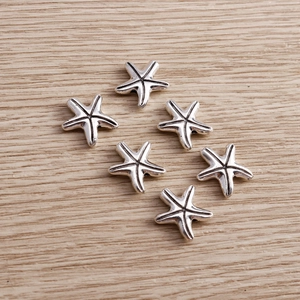Set of vintage alloy starfish charms for DIY jewelry making on a natural wood surface
