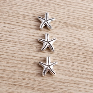 Detailed view of silver alloy starfish charms with intricate carved textures and a vintage finish
