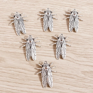 Set of retro silver cicada alloy pendants with vintage texture on wood background