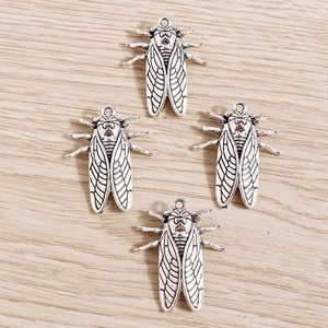 Set of retro silver cicada alloy pendants on wooden background for DIY jewelry making