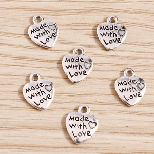 Set of heart-shaped alloy charms with 'Made with Love' engraving on wood background