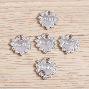 Silver alloy heart pendants with floral edges and LOVE AMOUR engravings on wood background