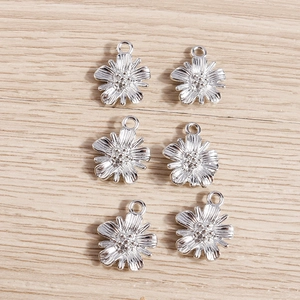Set of 6 silver daisy flower pendants in alloy for DIY jewelry making on wood background