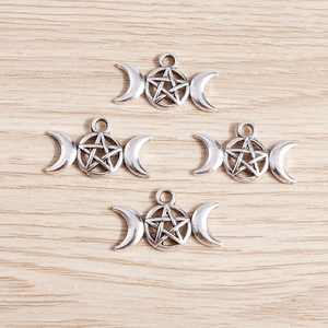 Détail macro de quatre breloques vintage en argent lune triple et pentagramme pour bijoux