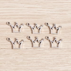 Vintage silver hollow crown charms in alloy for DIY jewelry making on wood background