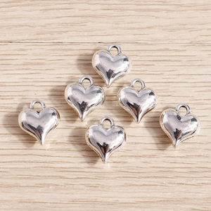 Polished silver heart pendants for DIY jewelry making on natural wood background