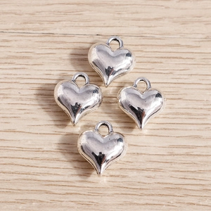 Macro detail of 3D silver heart charms with top holes for jewelry making on wood
