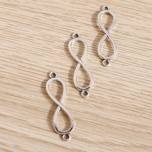 Vista macro de conectores de joyería infinito bañados en plata sobre madera